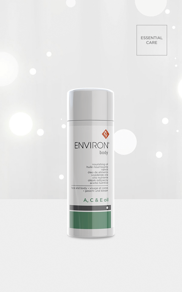 A white bottle of Environ A, C & E Body Oil, enriched with antioxidant vitamins, stands upright against a light background with white circles and “ESSENTIAL CARE” in the top right—perfect for nourishing sun-damaged skin.