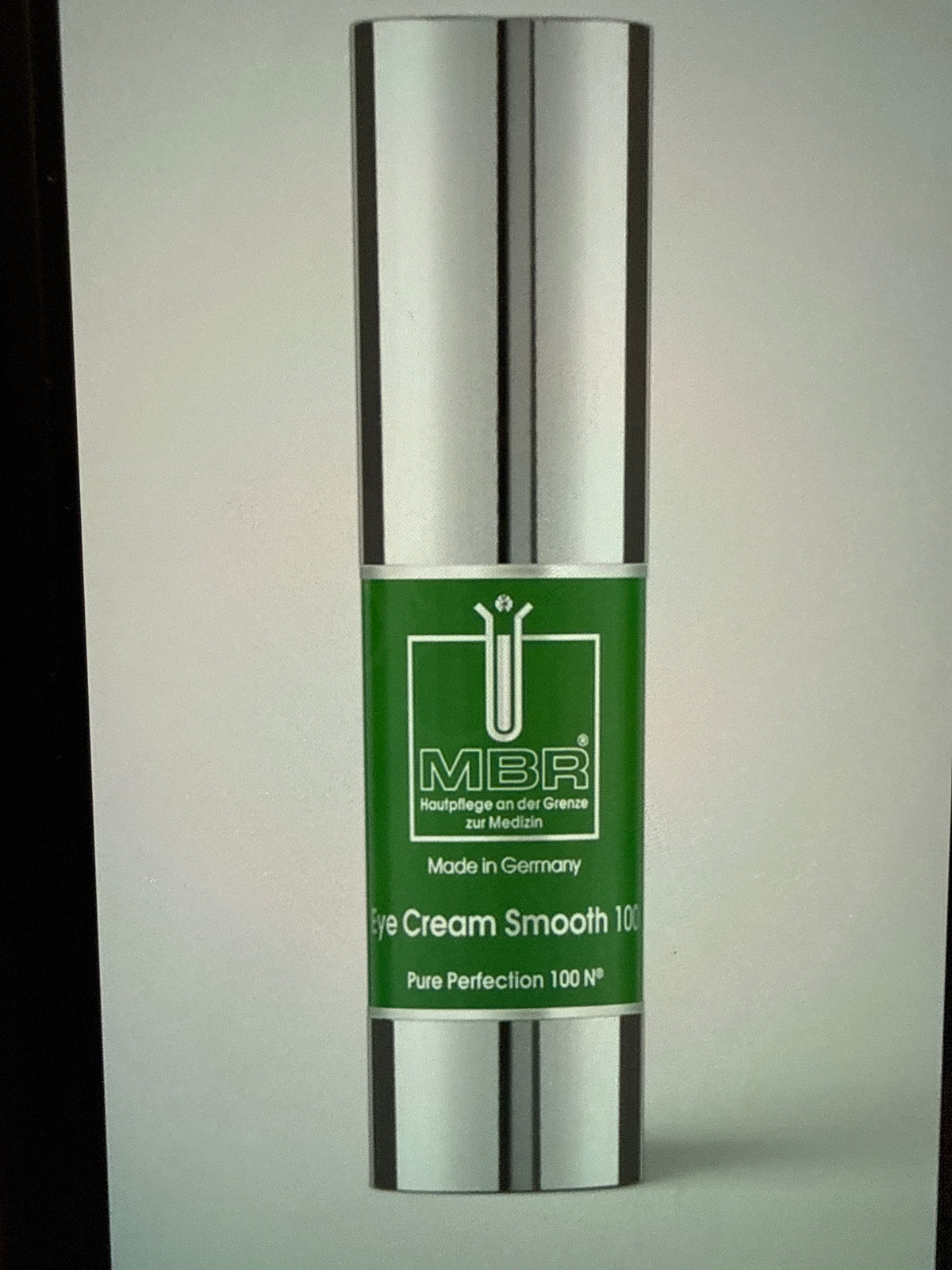 A silver and green bottle labeled Eye Cream Smooth 100 0.5 oz, featuring Pure Perfection 100 N° and Made in Germany on the front, this luxurious firming eye treatment is designed to reduce dark circles.
