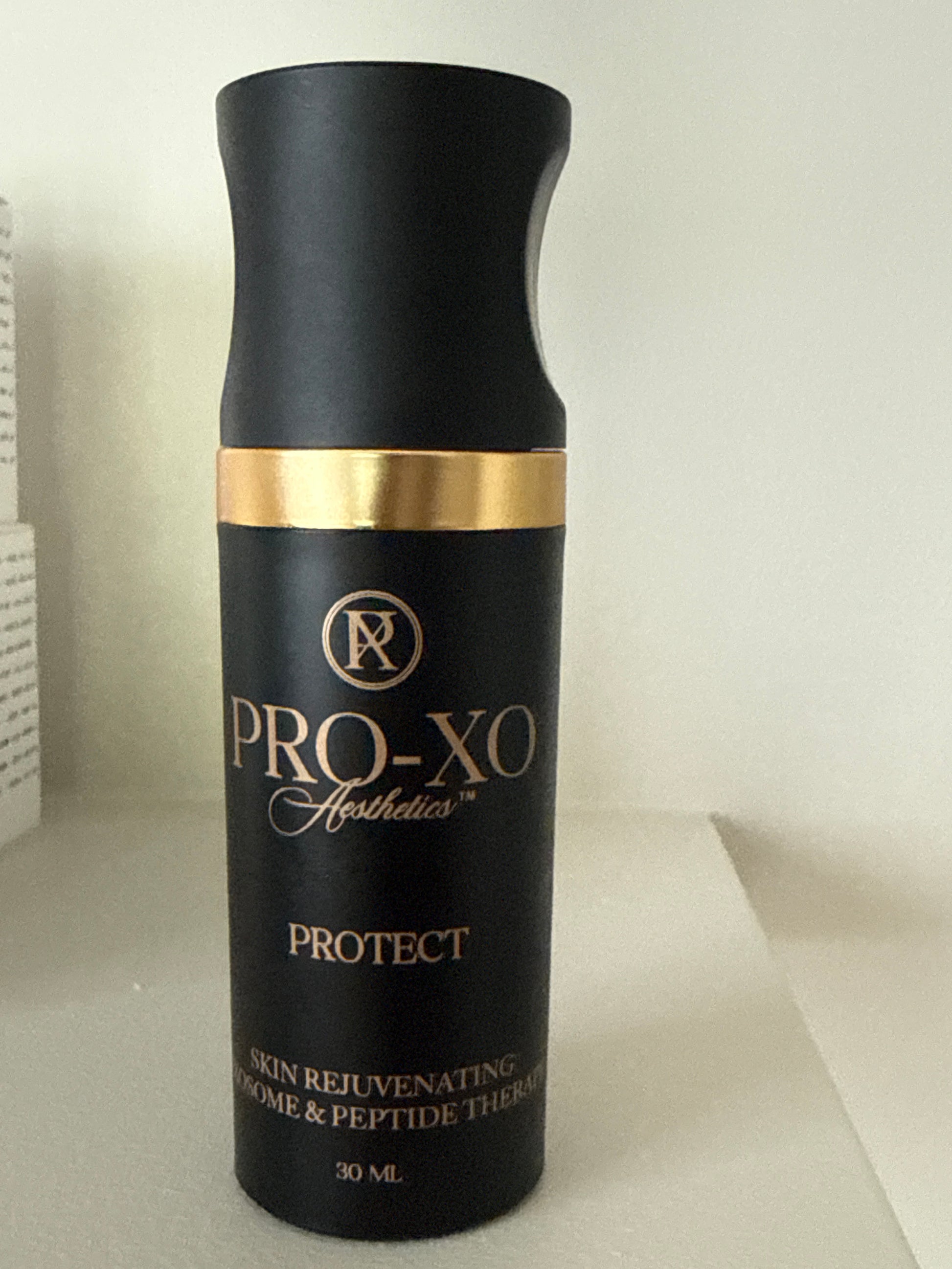 A black and gold bottle labeled Pro-Xo Protect, Advanced Skincare Rejuvenating Liposome & Peptide Therapy, 30 mL, standing on a light-colored surface.